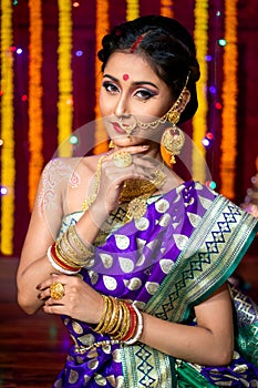 Indian Beautiful young girl wearing traditional sari making Flower rangoli for diwali or onam or Pongal Festival,Studio shot with