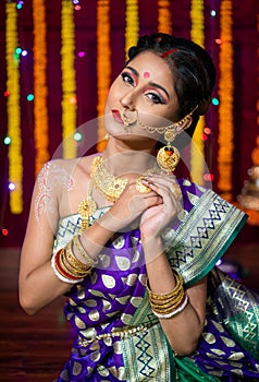 Indian Beautiful young girl wearing traditional sari making Flower rangoli for diwali or onam or Pongal Festival,Studio shot with