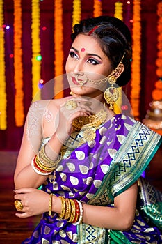 Indian Beautiful young girl wearing traditional sari making Flower rangoli for diwali or onam or Pongal Festival,Studio shot with