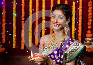 Indian Beautiful young girl wearing traditional sari making Flower rangoli for diwali or onam or Pongal Festival,Studio shot with