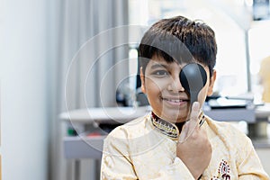 Indian boy examining eyesight checkup vision farsightedness examines ophthalmological hospital. doctor using occluder for eye photo
