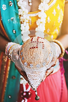 Indian bride with bangles on her wrist holding coconut shagun nariyal for indian marriage ritual