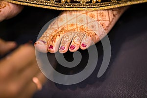 Indian bride feet coloring with indian henna paste or mehndi design of symbolic tattoos during a