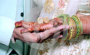 An Indian bride and groom holding their hands with ring during a Hindu wedding ritual