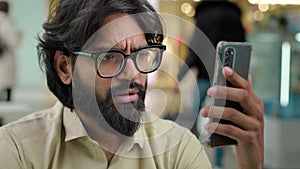 Indian business man Arabian businessman in glasses CEO worker talk mobile phone video call. Serious bearded executive