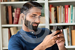 Indian business man holding smartphone using mobile phone at home or in office.