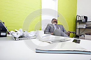 Indian businessman asleep at his desk clutching ukulele