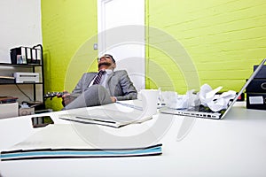 Indian businessman asleep at his desk clutching ukulele
