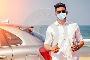 Indian businessman in car outdoors on sea beach summer good day.a man in a white shirt and mask rejoicing buying a new