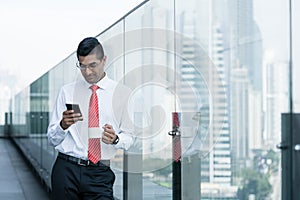 Indian businessman drinking coffee and using a smartphone