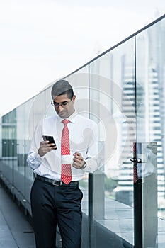 Indian businessman drinking coffee and using a smartphone