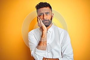 Indian businessman wearing white elegant shirt standing over isolated yellow background thinking looking tired and bored with