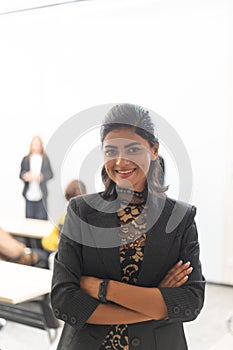 An Indian businesswoman smiling during a group of diverse employees business people team brainstorming meeting . Multiracial
