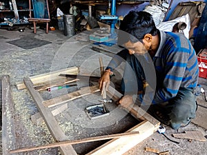 an indian carpenter hammering wood logs at workshop in India dec 2019