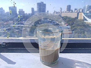 Indian cuttiing chai tea on glass window daylight