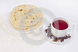 indian chapati bread. chapati on a white plate with a mug of red tea from pomegranate petals on a white background. cooking