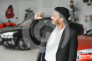 indian cheerful car salesman showing new car at showroom