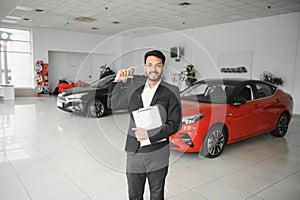 indian cheerful car salesman showing new car at showroom