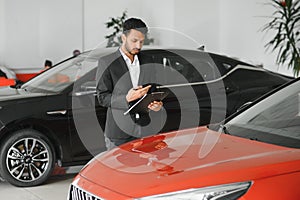 indian cheerful car salesman showing new car at showroom