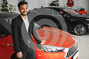 indian cheerful car salesman showing new car at showroom