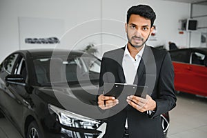 indian cheerful car salesman showing new car at showroom