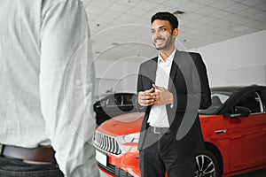 indian cheerful car salesman showing new car at showroom