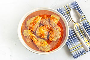 Indian Chicken Curry in a Bowl with Fork and Spoon on White Background