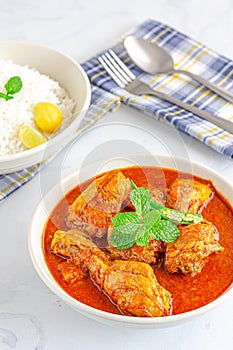 Indian Chicken Curry in a Bowl with Fork and Spoon on White Background