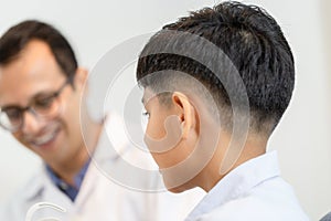 Indian child choosing eyeglasses in optics store, Boy doing eye test checking examination with optometrist in optical shop,