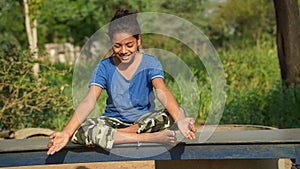 Indian Child doing exercise on platform outdoors. Healthy lifestyle. Yoga girl