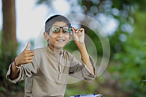 Indian child wearing spectacles and showing thumbs up