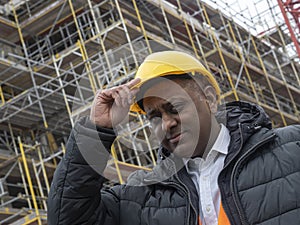 Indian civil engineer adjusting his safety helmet and looking at the camera