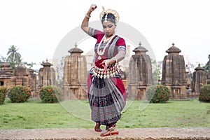 Indian classical Odissi dancer at Parsurameswara Temple with sculptures.