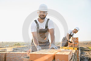 Indian construction workers work on the construction of a brick house. Construction of a brick wall