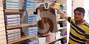 an indian cotton shopkeeper showing men part wear dress at shopping mall in india