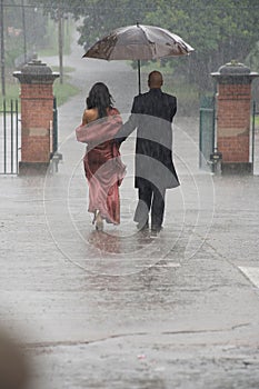 Indian couple holding an umbrella in the rain.