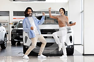 Indian couple shaking fists and dancing after buying new auto