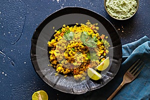 Indian cuisine. Poha or flattened rice typically Western Indian breakfast on black plate with coconut chutney sauce. national