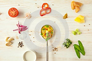 Indian curry masala with chicken and vegetables in bowl on white wooden board over bright background, top view. Healthy