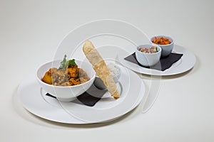 Indian Curry in a white bowl with rice on a white plate on a white background isolated