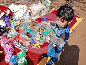 an indian cute little boy picking toys from street shop during fair program in India January 2020