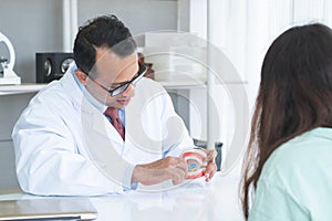 Indian dentist man holding jaw model and toothbrush at clinic. Middle aged doctor demonstrating right way to clean teeth and gums