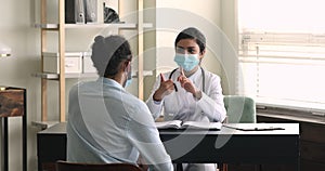 Indian doctor wear facemask talks to patient about medication list