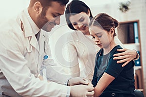 Indian doctor seeing patients in office. Doctor is putting patch on daughter`s arm. photo