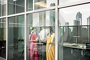 Indian employees sticking reminders on glass wall in the office photo
