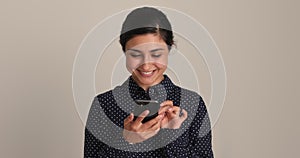 Indian ethnicity young woman holding smartphone, studio shot