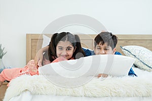 Indian family, brother and sister with traditional clothes lying on bed and white pillow, two children smiling and hugging