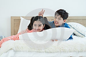 Indian family, brother and sister with traditional clothes lying on bed and white pillow, two children smiling and playing