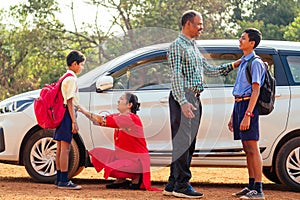Indian family driving boys to school In front of house gates
