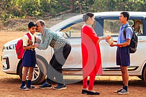 Indian family driving boys to school In front of house gates